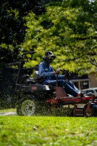 person on a lawn mower cutting grass in an HOA community in DFW Texas